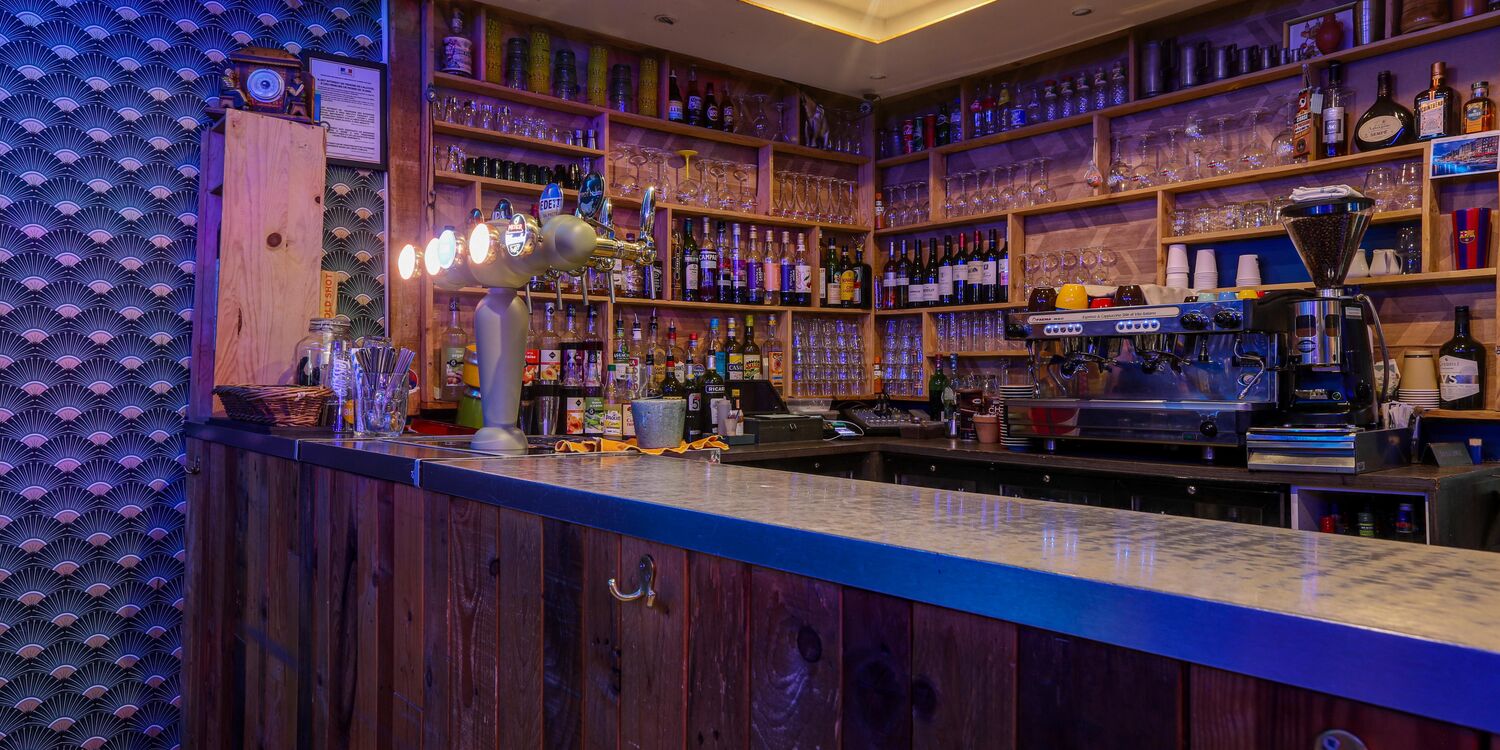 Le comptoir en bois, les bouteilles et la salle de la brasserie